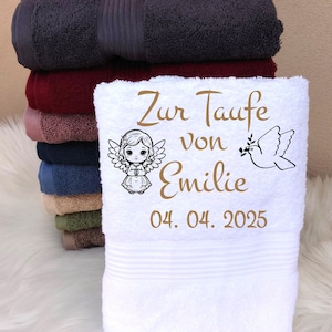 May include: A stack of colorful bath towels, with a white towel in front. The white towel is personalized with the text "Zur Taufe von Emilie 04. 04. 2025", an angel illustration, and a dove illustration.