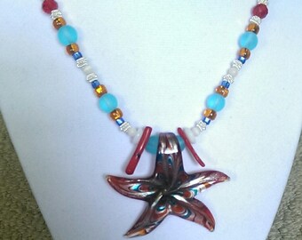 May include: A turquoise, red, and brown beaded necklace with a red and orange starfish pendant.