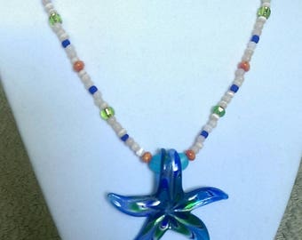 May include: A blue glass starfish pendant necklace with a multi-colored bead chain. The chain features white, blue, green, and orange beads.