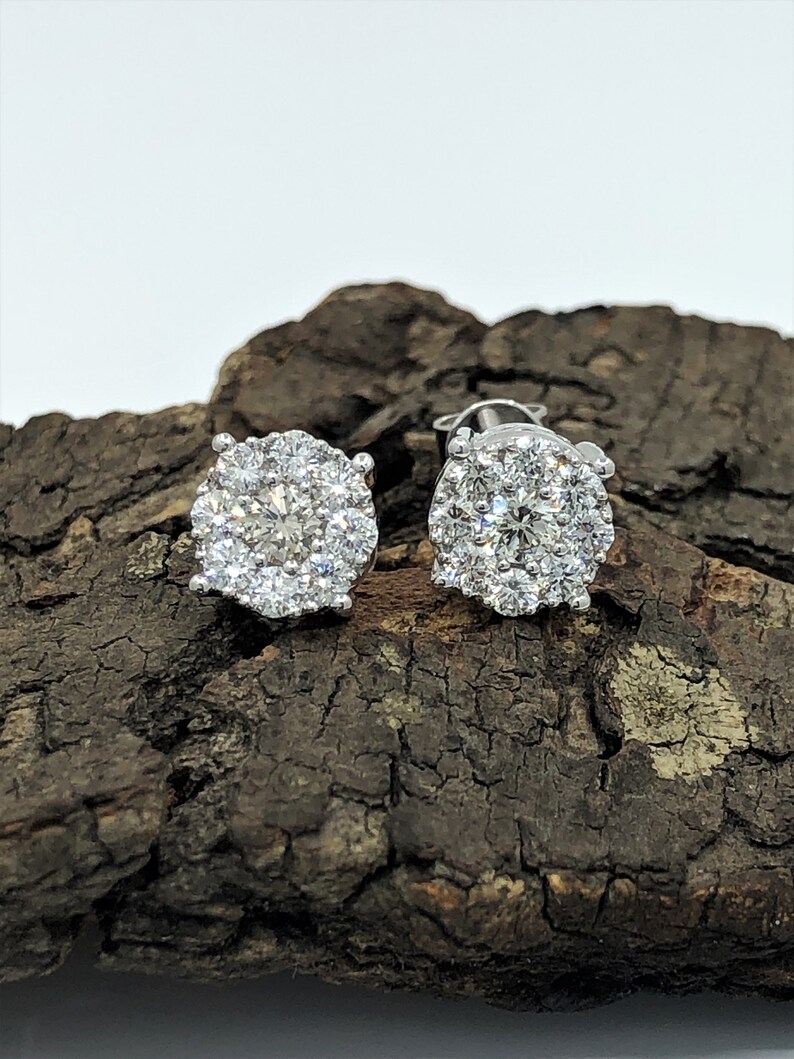 May include: A pair of silver stud earrings with a round halo of small diamonds.