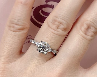 May include: A silver engagement ring with a large round center diamond and smaller diamonds set in a delicate band.