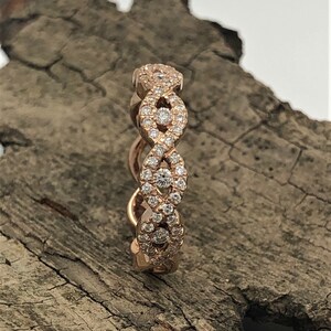 May include: A rose gold band ring with a delicate, interwoven design set with small, sparkling diamonds.
