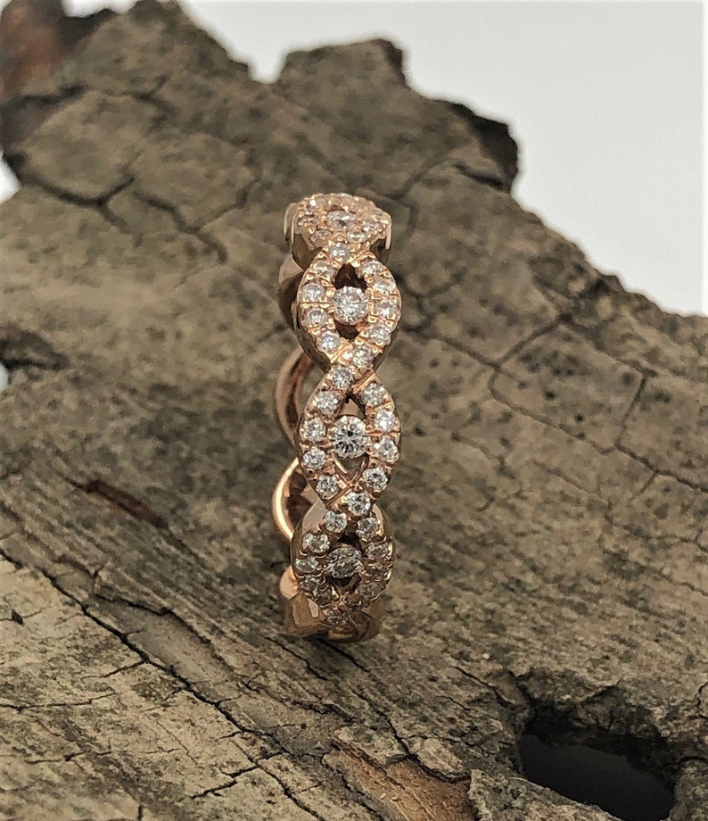 May include: A rose gold band ring with a delicate, interwoven design set with small, sparkling diamonds.