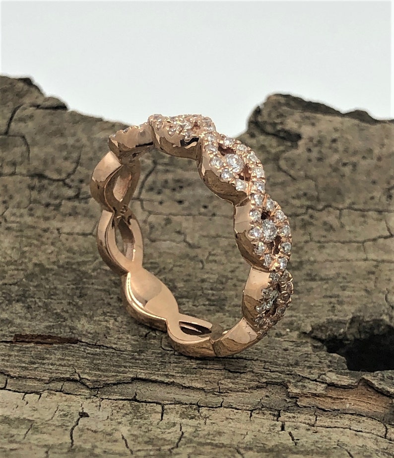 May include: A rose gold band ring with a delicate, intertwined design featuring small diamonds.