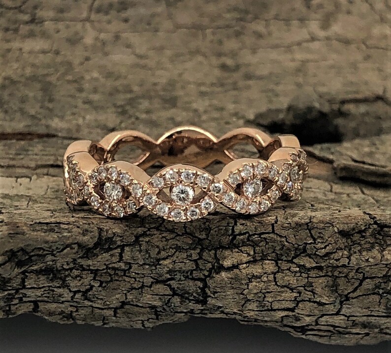 May include: A rose gold band ring with a delicate design of interlocking ovals set with small diamonds.