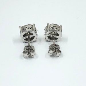 May include: A pair of silver earrings with a round, textured design. The earrings are marked "G14K" on the back.