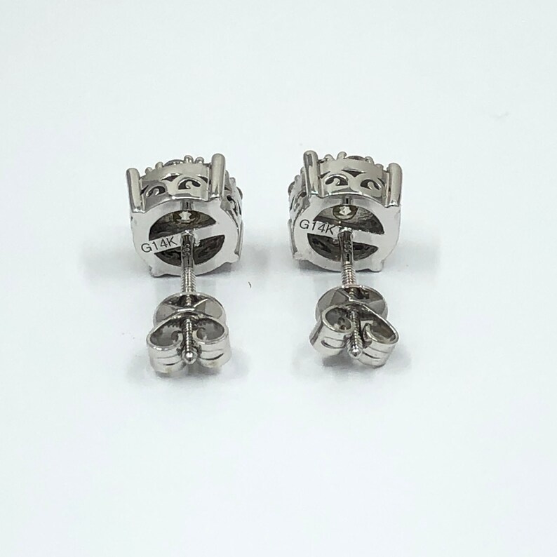 May include: A pair of silver earrings with a round, textured design. The earrings are marked "G14K" on the back.