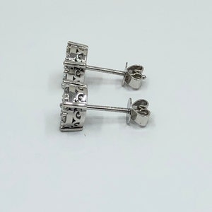 May include: A pair of silver stud earrings with a round, ornate design. The earrings have a post and butterfly back.
