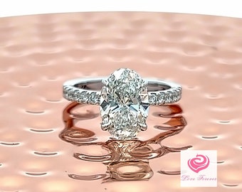 May include: A silver ring with a large oval-shaped diamond set in a pave setting. The ring is on a copper-colored surface.