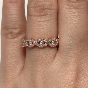May include: A rose gold band ring with a delicate, wavy design featuring small diamonds.