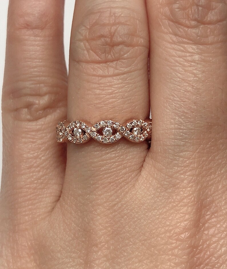 May include: A rose gold band ring with a delicate, wavy design featuring small diamonds.