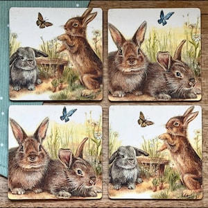 May include: Set of four coasters featuring a brown rabbit with a butterfly design. Each coaster has a different rabbit and butterfly design.