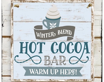 May include: A rustic wooden sign with a light blue background and a distressed white frame. The sign features the words "HOT COCOA BAR" in teal, with "WINTER BLEND" and "WARM UP HERE!" in gray. A graphic of a cocoa cup with whipped cream is at the top.