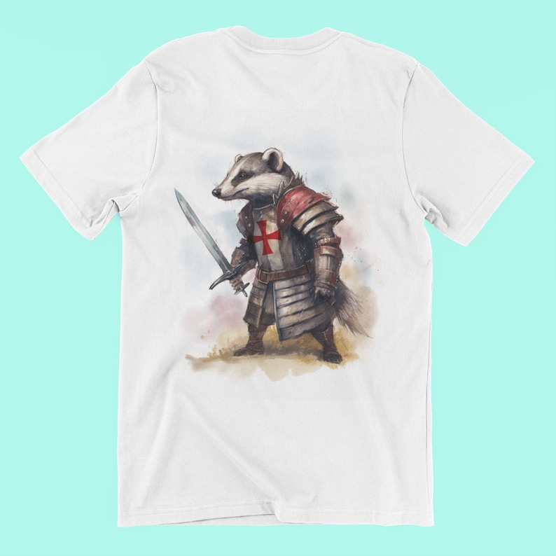 Pode incluir: Camiseta branca com uma ilustra&ccedil;&atilde;o em aquarela de um texugo com armadura de cavaleiro, segurando uma espada. A armadura inclui uma cruz vermelha no peito. O texugo tem uma express&atilde;o s&eacute;ria, e o desenho est&aacute; centrado.