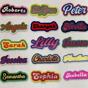 May include: A selection of embroidered name patches in various colours. Names include "Roberts", "Lily Grace", "Peter", "Angela", "Zhanyak", "Neville", "Sarah", "Lilly", "Jaxson", "Jessica", "Charlotte", "Heather", "Samantha", "Sophia", and "Isabella".