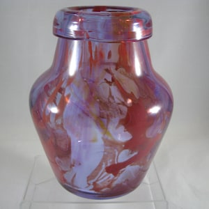 May include: A glass vase with a wide mouth and a rounded body. The vase is made of iridescent glass with a swirling pattern of red, white, and purple.
