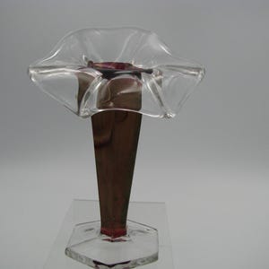 May include: A clear glass vase with a flared top and a brown stem. The vase has a unique shape, with a wide, ruffled opening. The base is a clear, geometric shape. The vase is likely for decorative purposes.