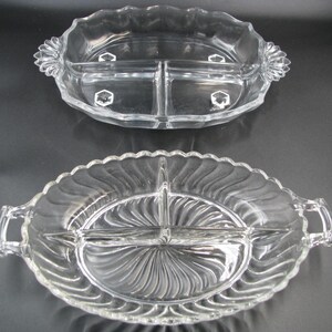 May include: Two clear, divided serving dishes. The top dish is oval with a scalloped edge and a floral design on the handles. The bottom dish has a similar shape, with a wavy pattern and handles. Both dishes have three compartments.