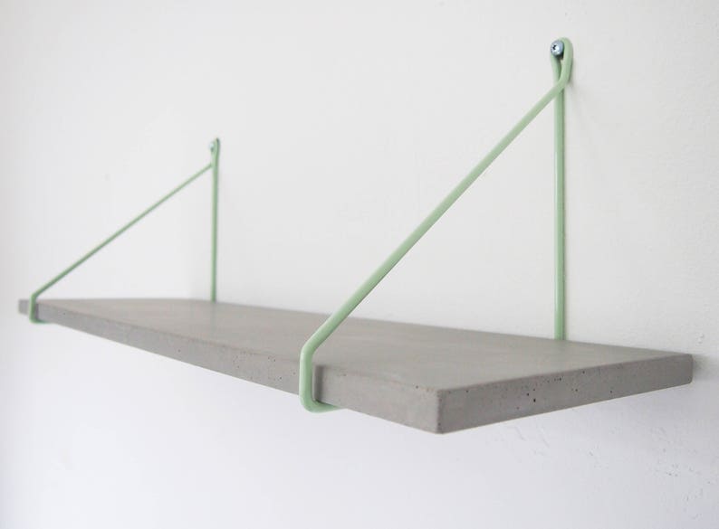 May include: A concrete shelf with light green metal brackets. The shelf is mounted to a white wall.