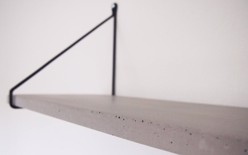 May include: A concrete shelf with a black metal bracket. The shelf is light gray and has a rough texture.