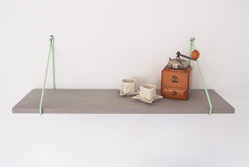 May include: A gray wooden shelf with two white ceramic cups and a vintage coffee grinder on top. The shelf is suspended from the ceiling with two light green cords.