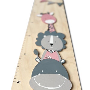 May include: A wooden growth chart with a ruler marked in inches. The chart features a gray and pink painted hippopotamus, lion, and giraffe.
