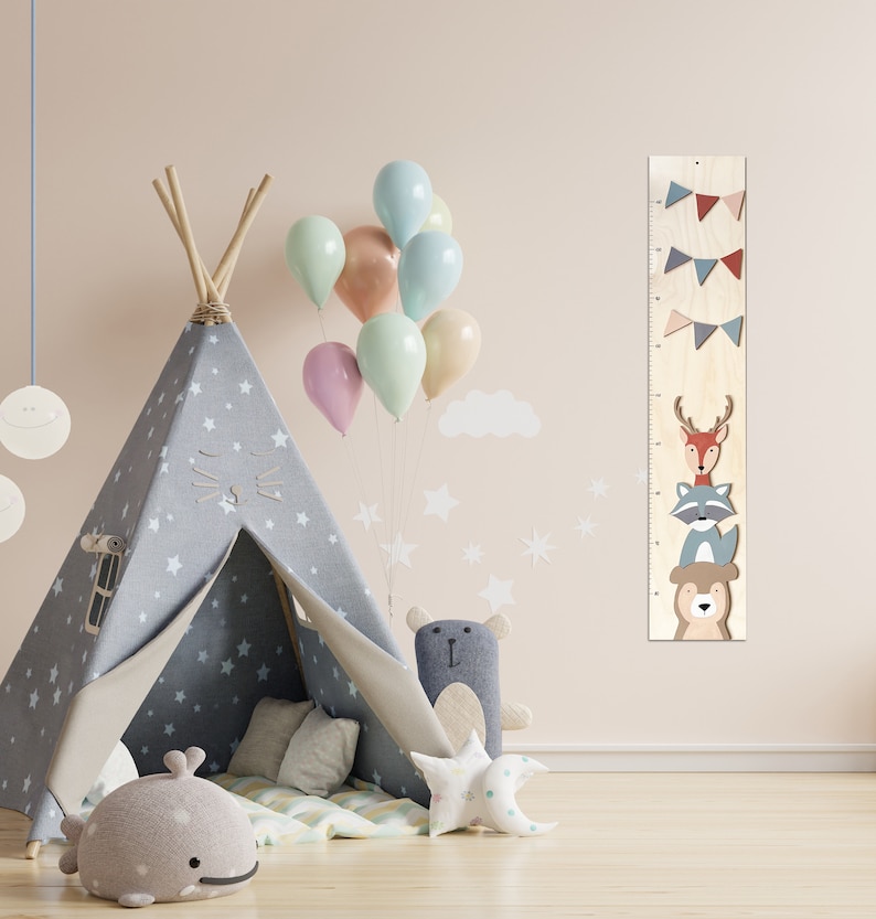 May include: A wooden growth chart with a deer, raccoon, and bear design. The chart is decorated with colorful flags and stars. A teepee tent, stuffed animals, and balloons are in the background.