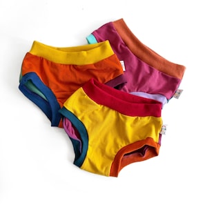 May include: Three pairs of colourful cotton underwear with rainbow stripes. The underwear is made of soft, comfortable fabric and has a wide waistband.