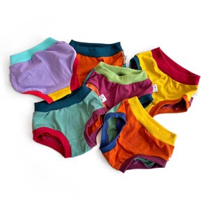 May include: A set of six colourful underwear with different colour combinations. Each pair has a contrasting coloured waistband. The underwear is made of soft, comfortable fabric.