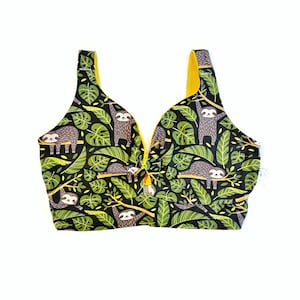 May include: A black and green crop top with a yellow trim and a print of sloths hanging from branches in a jungle setting.