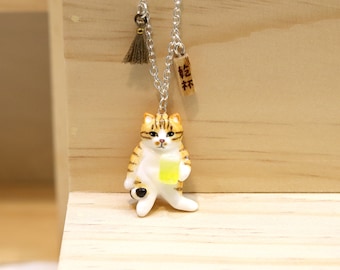 May include: A silver chain necklace with a small wooden charm that says "抹茶" (Matcha) and a ceramic cat figurine holding a glass of green liquid. The cat is white with orange and brown stripes.