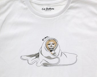 May include: White t-shirt with a cartoon illustration of a cat wrapped in a blanket. The cat is looking at the viewer with a grumpy expression. The text "Cat Brothers" is printed on the shirt's tag and the text "ニャー" is printed on the shirt.