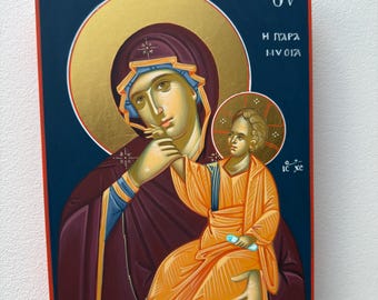 Könnte beinhalten: Eine Ikone, die eine religiöse Figur zeigt, die ein Kind hält. Die Figuren tragen orangefarbene und violette Gewänder vor einem dunkelblauen Hintergrund mit goldenen Akzenten. Die Ikone hat griechischen Text und einen roten Rand.