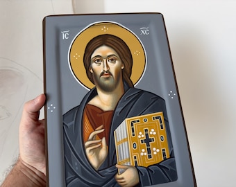 May include: A hand-painted icon of Jesus Christ holding a book. The icon is painted on a wooden panel with a gray background and a gold halo around Jesus' head. The text "IC XC" is written in the top corners of the icon.