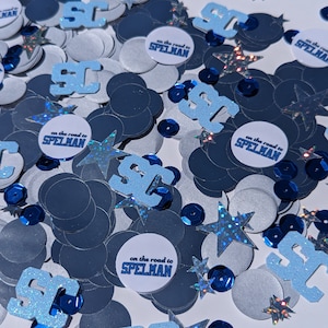 May include: Blue and white confetti with the words "on the road to SPELMAN" on several of the circles. The confetti also includes blue and silver stars and circles.