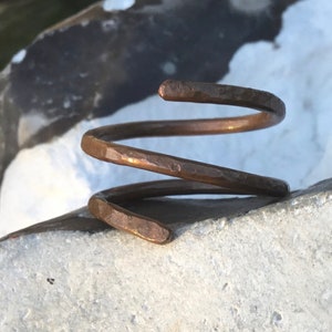 Pode incluir: Um anel de cobre martelado com um design em espiral.