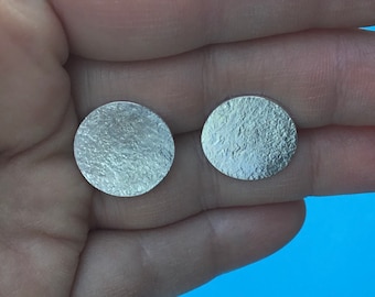 May include: A pair of silver round earrings with a textured surface.