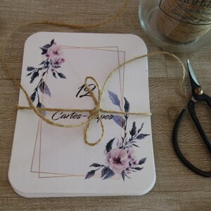 May include: A stack of white cards with a floral design and gold accents. The cards are tied together with twine and the text "12 Cartes - Pages" is visible.