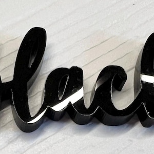 Puede incluir: La palabra "black" en acrílico negro en una fuente cursiva.