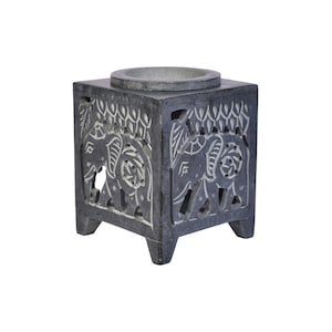 May include: A grey stone incense burner with an intricate carved design of elephants. The burner has a square base with four legs and a round top for holding incense.