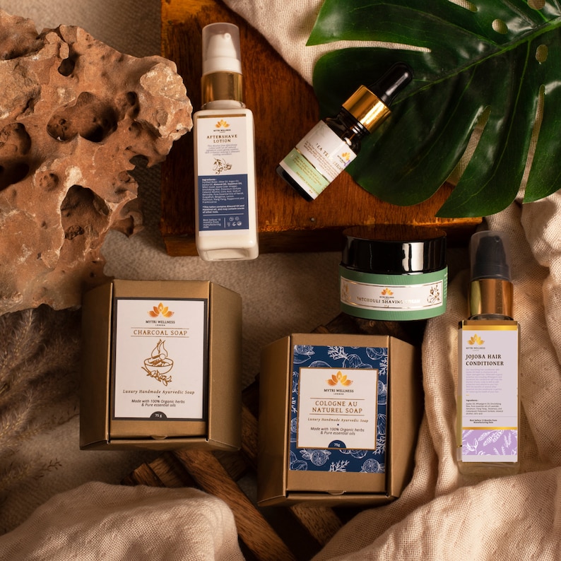 Puede incluir: Una colecci&oacute;n de productos de belleza naturales que incluyen un jab&oacute;n de carb&oacute;n vegetal, un jab&oacute;n de colonia, un acondicionador para el cabello de jojoba, una loci&oacute;n para despu&eacute;s del afeitado y un aceite esencial. Los productos est&aacute;n empaquetados en cajas doradas y azules con un tema natural.