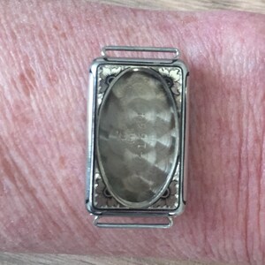 May include: Silver watch with a floral design on the back. The watch face is visible through the back and has the text "1951" printed on it.