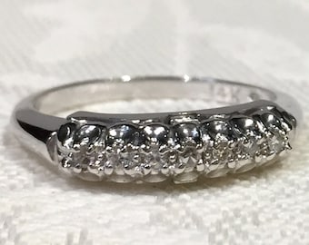 Op de afbeelding: Een zilveren bandring met een rij kleine diamanten in een delicaat ontwerp.