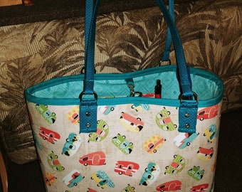 May include: A teal tote bag with a zipper closure and two teal handles. The bag is made of a fabric with a pattern of colorful vintage campers on a beige background.