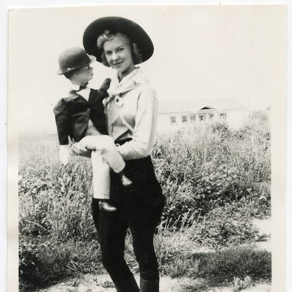 vintage vernacular snapshot 1930s? cute cowgirl gal with ventriloquist's dummy friend. he is looking at her provocatively I think