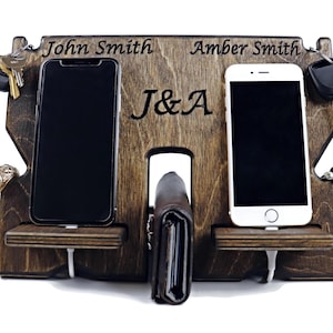 May include: A wooden phone and key holder with two phone slots, a wallet slot, and key hooks. The holder is personalized with the names "John Smith" and "Amber Smith" and the initials "J&A".