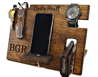 May include: A wooden organiser with the text "Dad's Stuff" engraved on the top. It has slots for a phone, watch, keys, glasses, and a wallet.