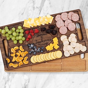 May include: A walnut wood serving tray with compartments for cheese, crackers, fruit, and other snacks. The tray has a personalized inscription that reads "The Jacksons".