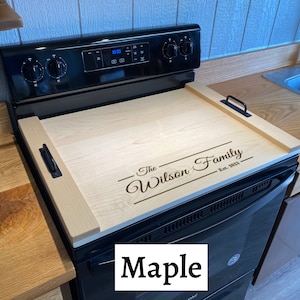 Full Size Maple Stovetop cover sitting on a range with an engraving on the lower half of it.