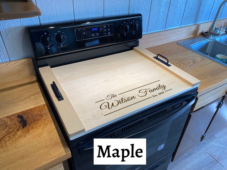 Full Size Maple Stovetop cover sitting on a range with an engraving on the lower half of it.